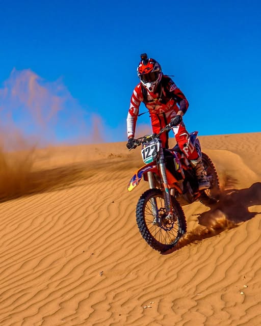 Dirt bike rider jumping high against a deep blue sky